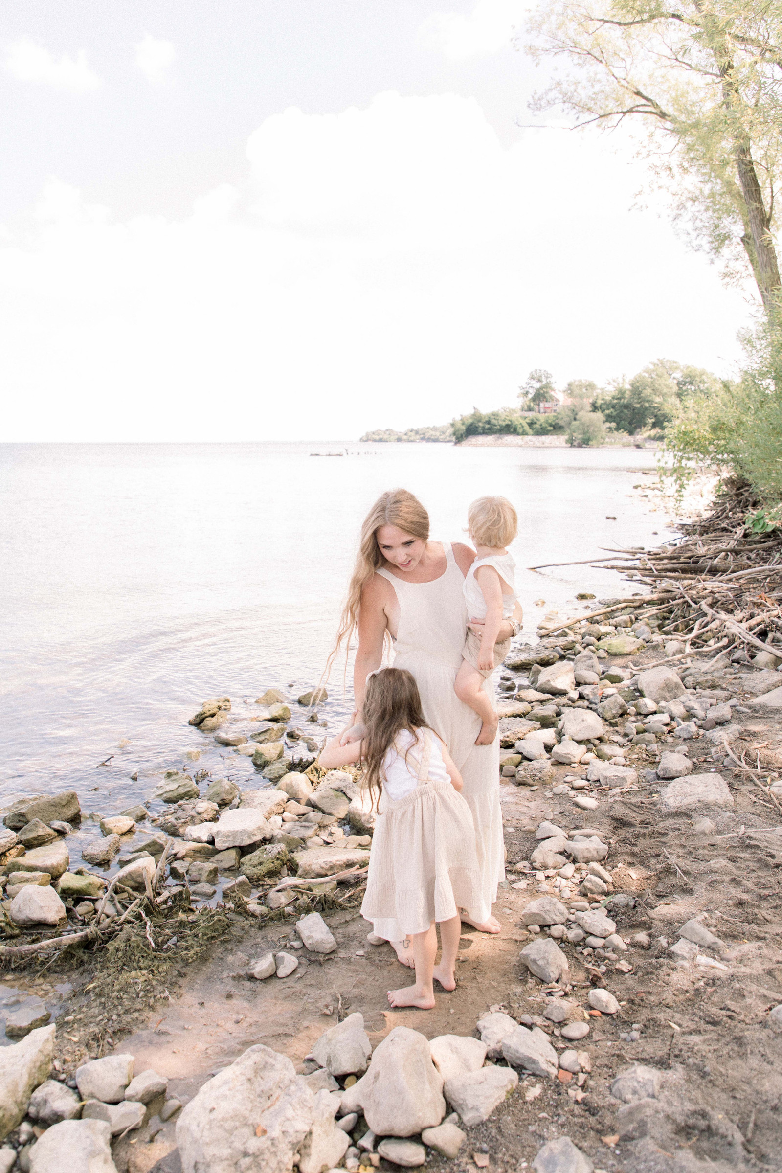 Portrait of mother with two small children standing together at the beach. Niagara family photographer, Niagara portrait photographer, Niagara motherhood photographer, candid photography, light & airy photography, Emily VanderBeek Photography.