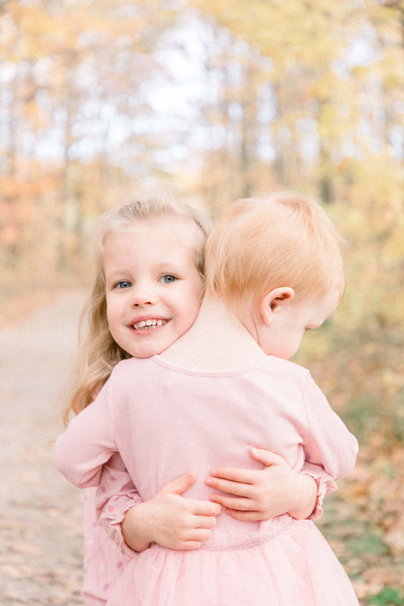Portrait of two sister hugging each other with a fall background. Emily VanderBeek Photography, Portrait and Family Photography, Niagara Photographer, Champlain Photographer, Vaudreuil-Soulanges Photographer, candid photography, authentic photography.