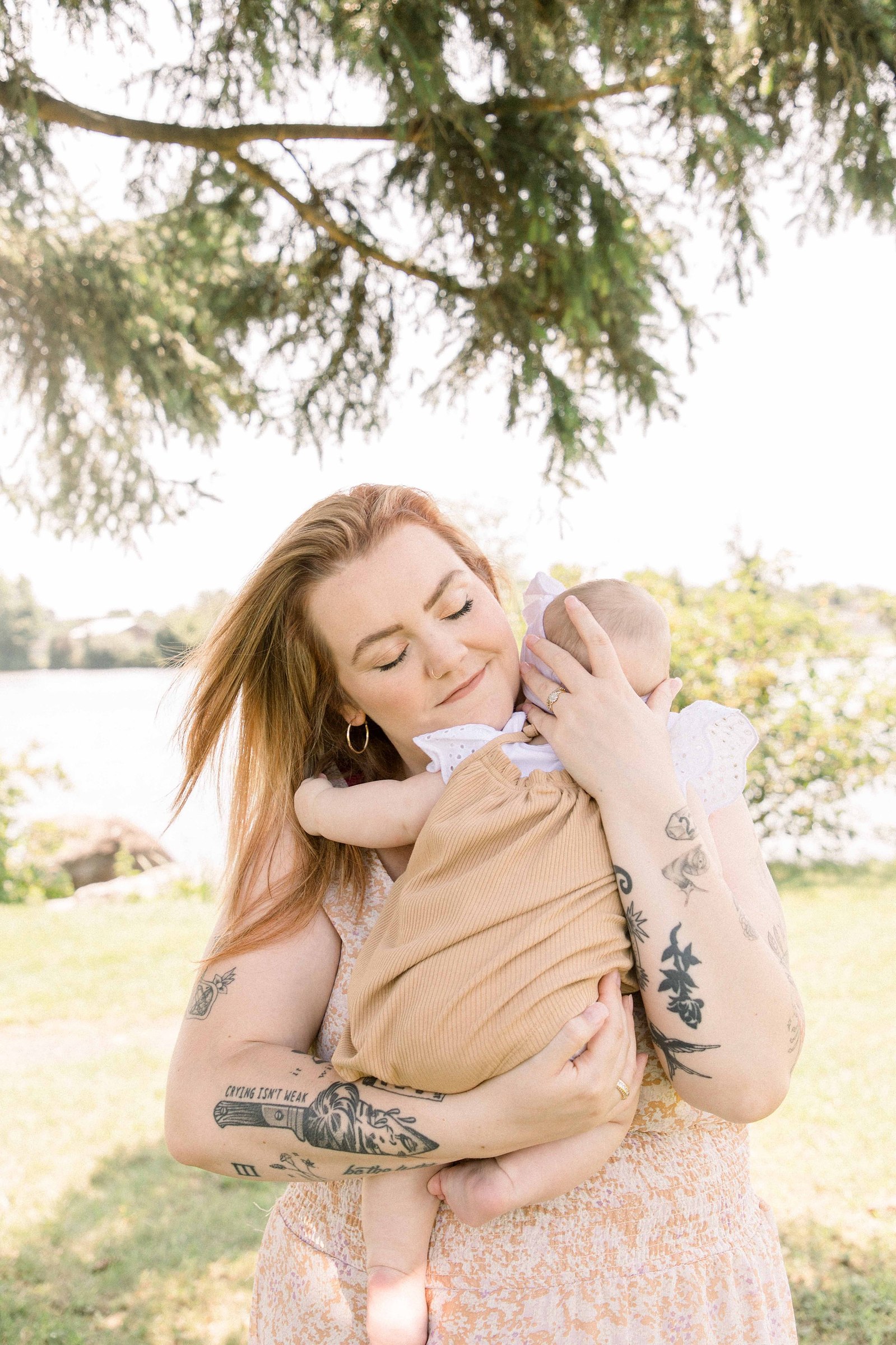 Candid portrait of a mom hugging her baby girl in front of the Ottawa River in Hawkesbury, Portrait Photographer, Family Photographer, Emily VanderBeek Photography, Candid Photography, making memories.