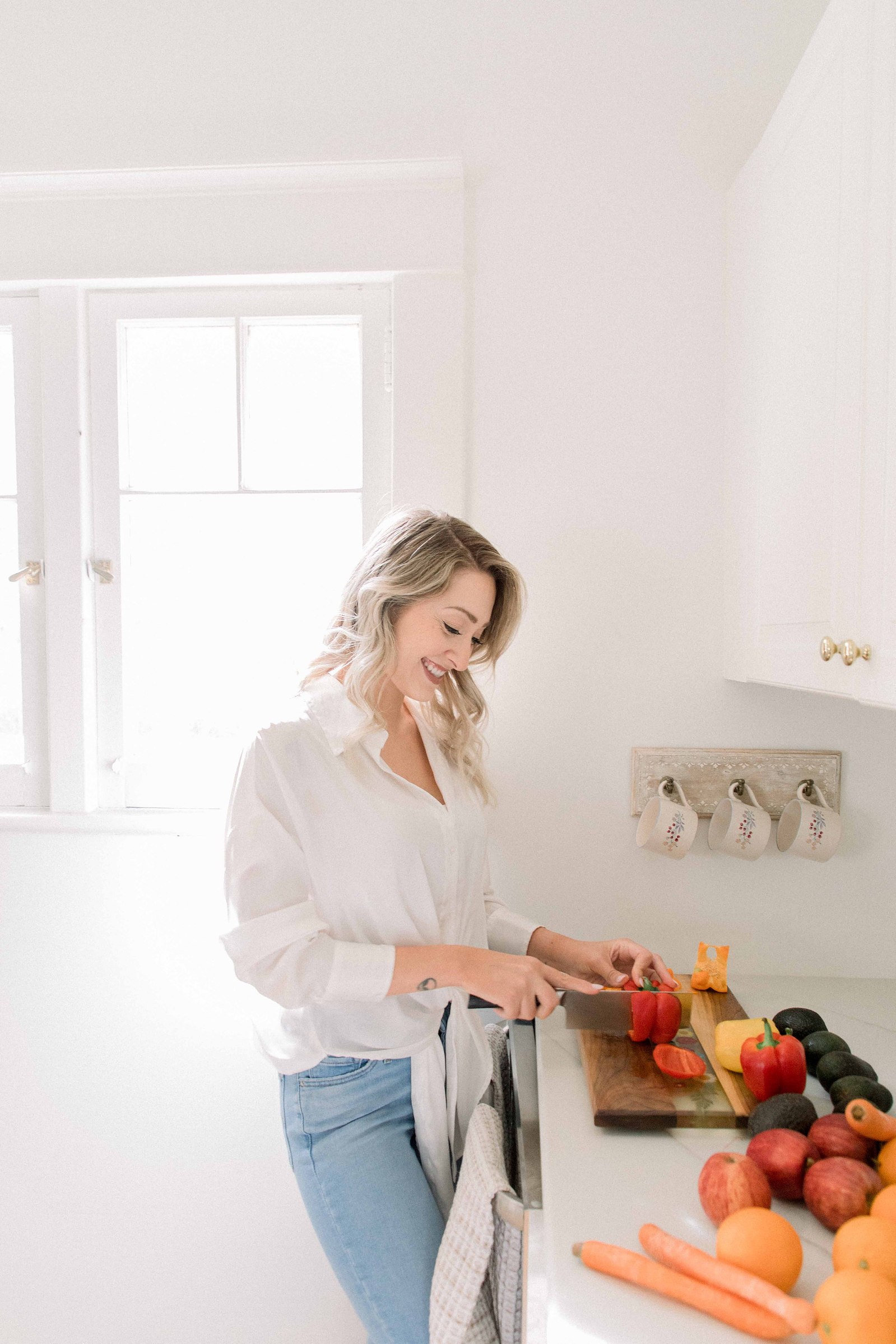 Portrait of a woman chopping fruit in a studio kitchen. Light and airy photography. Emily VanderBeek Photography. Niagara Photographer, Ottawa Photographer, Montreal Photographer.
