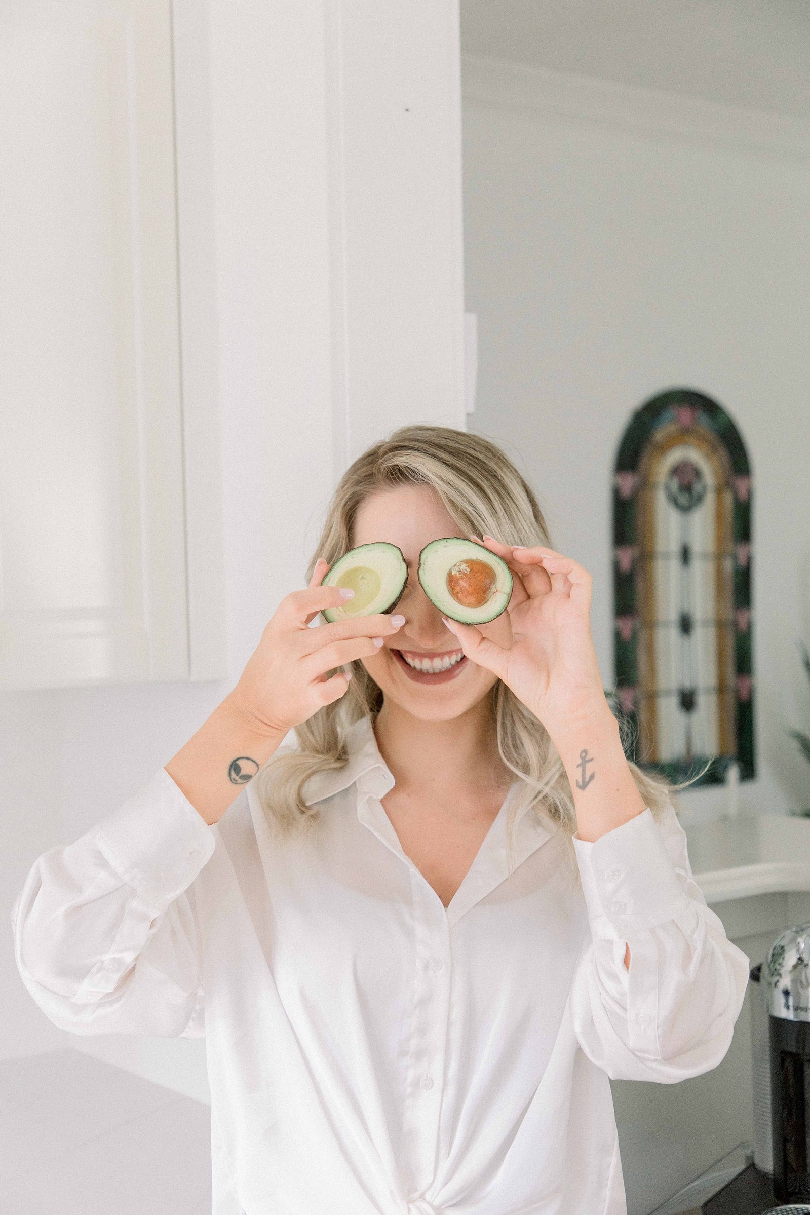 Portrait of a woman holding avocados in front of her eyes. Light and airy photography. Emily VanderBeek Photography. Niagara Photographer, Ottawa Photographer, Montreal Photographer.