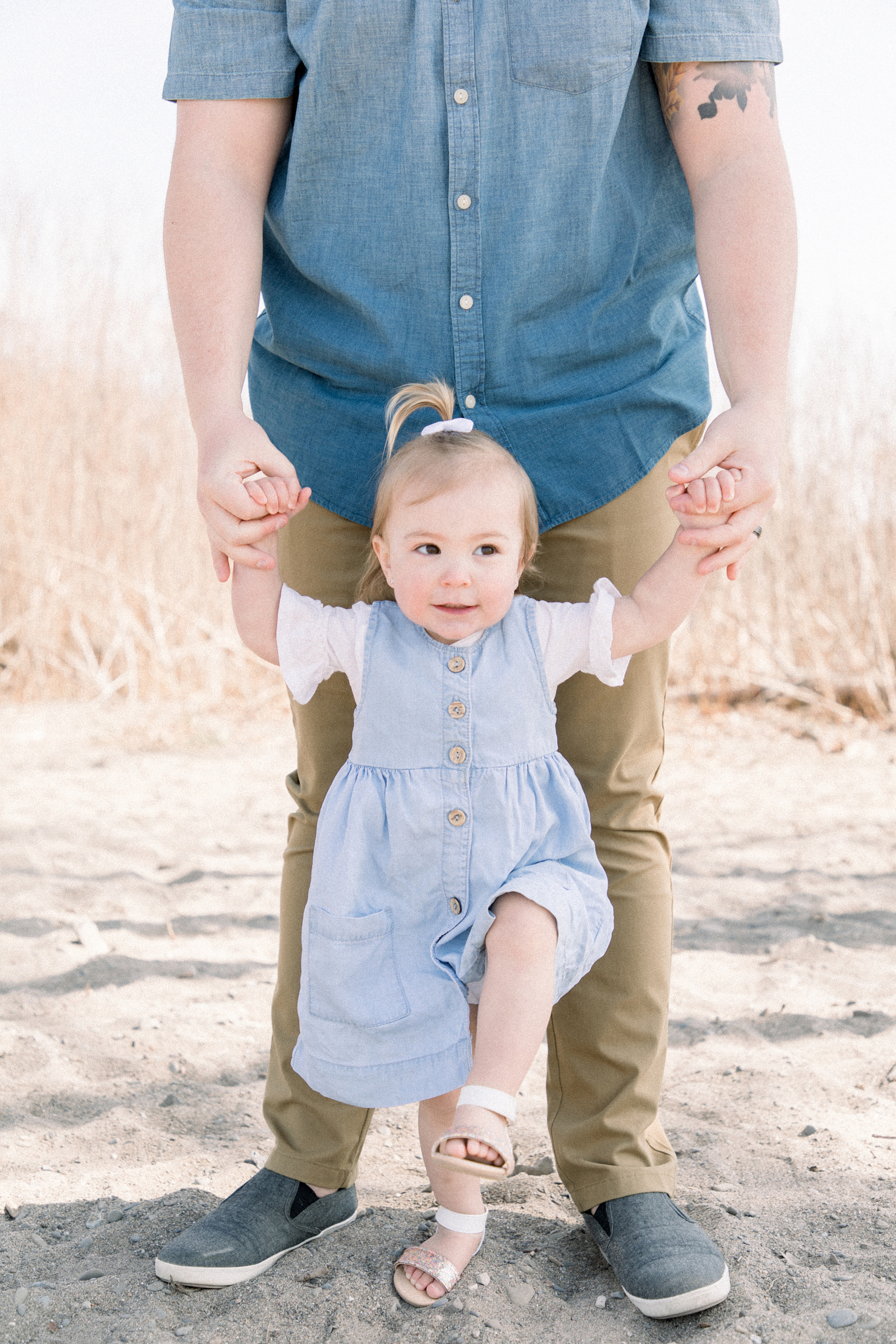 Portrait of a daughter standing in front of her father holding his hands on the beach, Niagara family photography, beach session