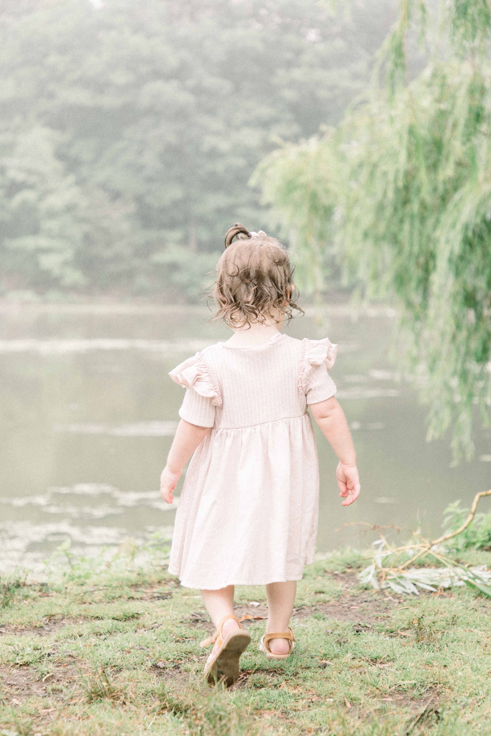Portrait of little girl walking towards the water by a willow tree, Niagara Portrait Photographer, Niagara Family Photographer, Niagara Motherhood Photography, Beach Portrait Photography, Emily VanderBeek Photography.