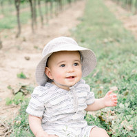 Candid portrait of little boy sitting in a vineyard smiling, Emily VanderBeek Photography, Portrait and Family photography, Niagara Photographer, Champlain Photographer, Vaudreuil-Soulanges Photographer, candid photography, authentic photography.