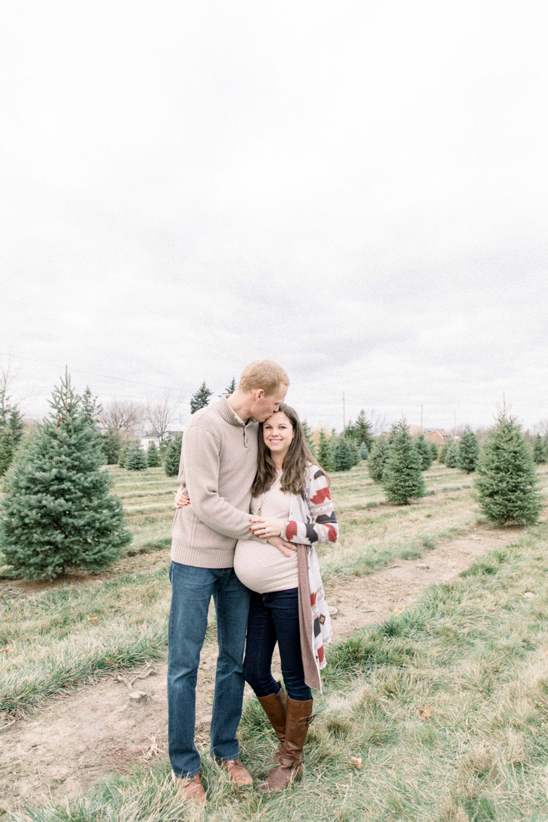 Maternity photo of man hugging woman on Christmas tree farm, Emily VanderBeek Photography, Portrait and Family photography, Niagara Photographer, Champlain Photographer, Vaudreuil-Soulanges Photographer, candid photography, authentic photography.