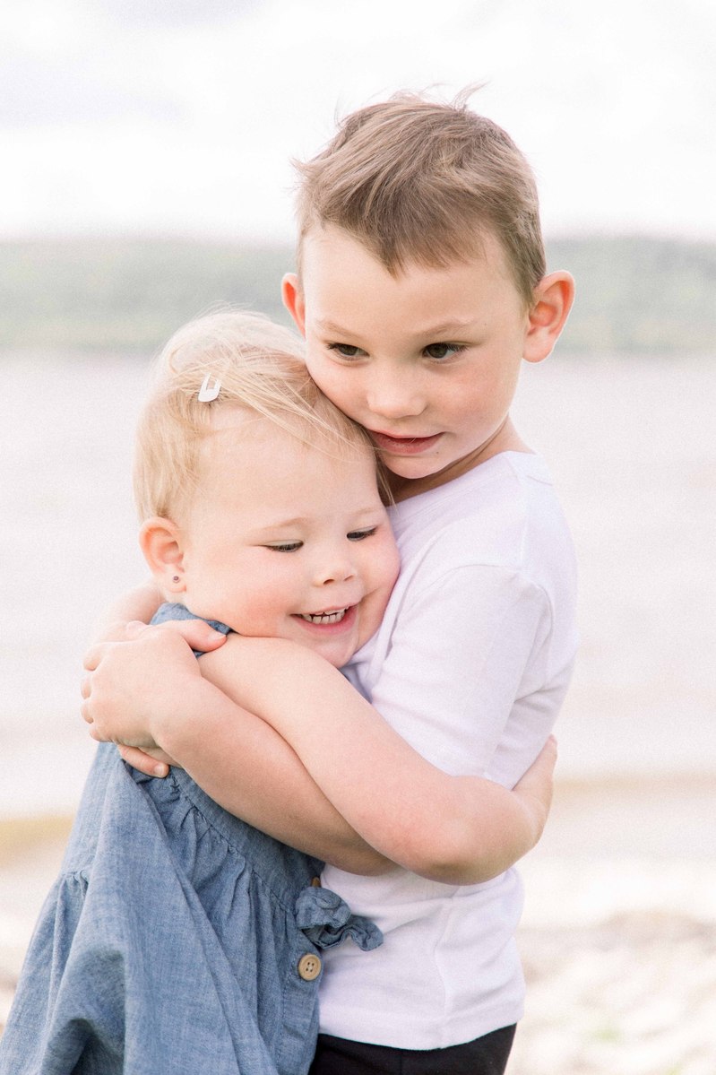 Portrait of big brother hugging little sister by the beach. Emily VanderBeek Photography, Portrait and Family photography, Niagara Photographer, Champlain Photographer, Vaudreuil-Soulanges Photographer, candid photography, authentic photography.