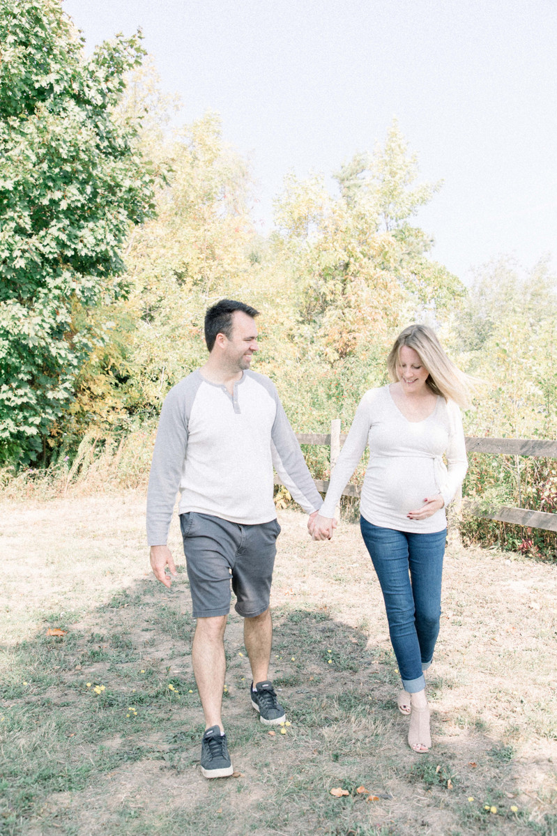 Maternity photo of man and woman walking together looking at bump, Emily VanderBeek Photography, Portrait and Family photography, Niagara Photographer, Champlain Photographer, Vaudreuil-Soulanges Photographer, candid photography, authentic photography.