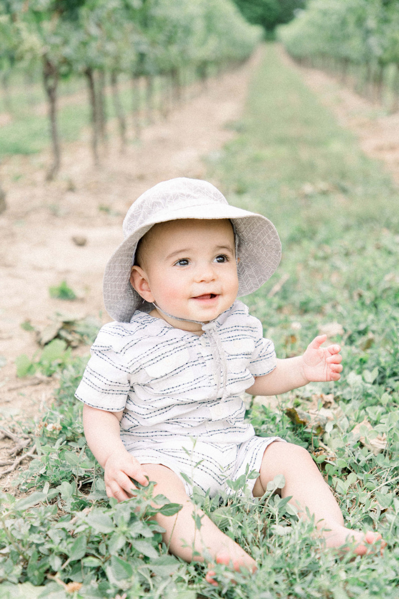 Candid portrait of little boy sitting in a vineyard smiling, Emily VanderBeek Photography, Portrait and Family photography, Niagara Photographer, Champlain Photographer, Vaudreuil-Soulanges Photographer, candid photography, authentic photography.