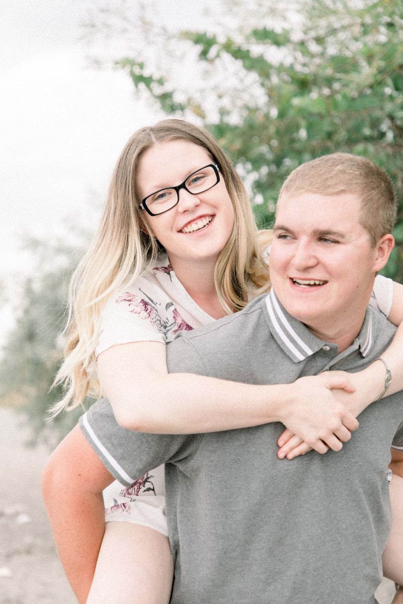 Candid portrait of man giving woman a piggy back on the beach, Emily VanderBeek Photography, Portrait and Family photography, Niagara Photographer, Champlain Photographer, Vaudreuil-Soulanges Photographer, candid photography, authentic photography.