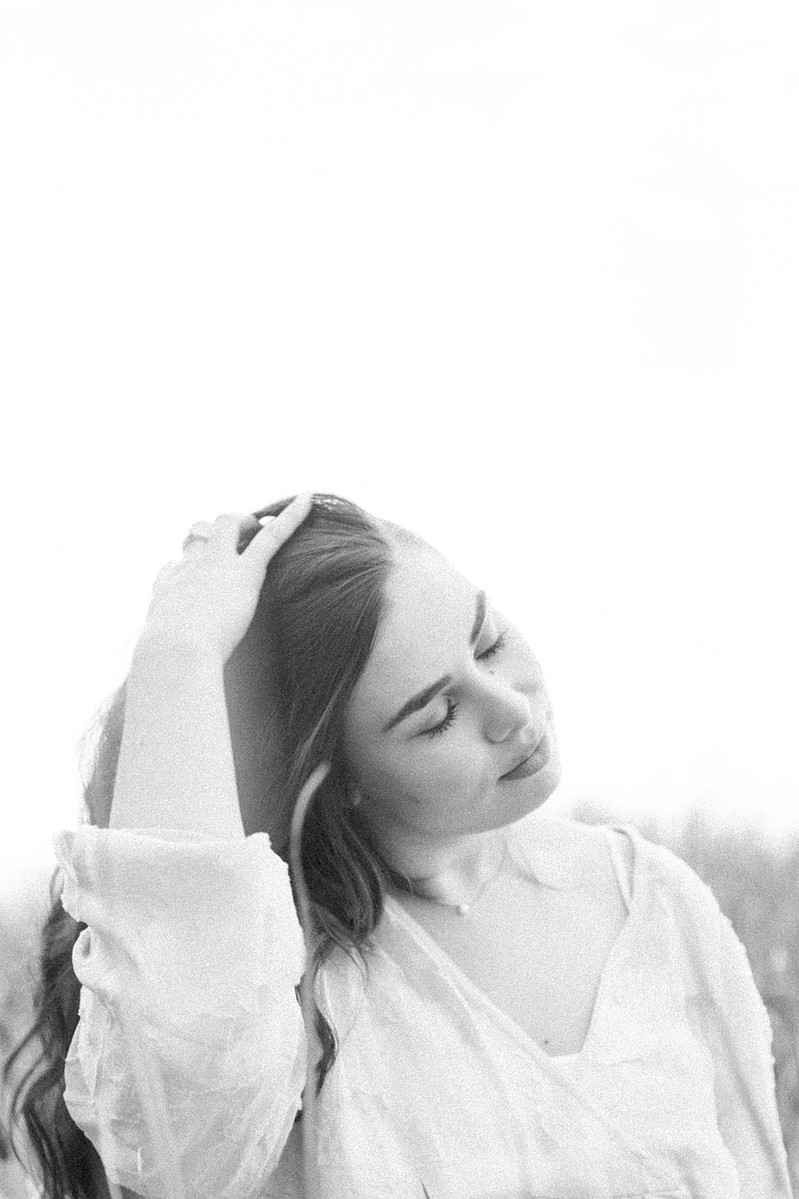 Black and white candid photo of woman playing with her hair on beach, Emily VanderBeek Photography, Portrait and Family photography, Niagara Photographer, Champlain Photographer, Vaudreuil-Soulanges Photographer, candid photography, authentic photography.