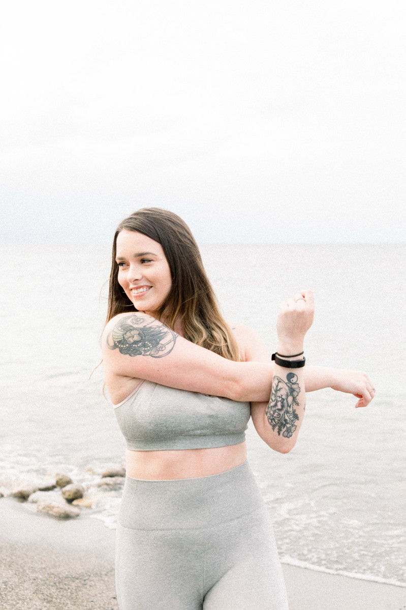 Photo of woman stretching arm muscles in activewear on beach, Emily VanderBeek Photography, Portrait and Family photography, Niagara Photographer, Champlain Photographer, Vaudreuil-Soulanges Photographer, candid photography, authentic photography.