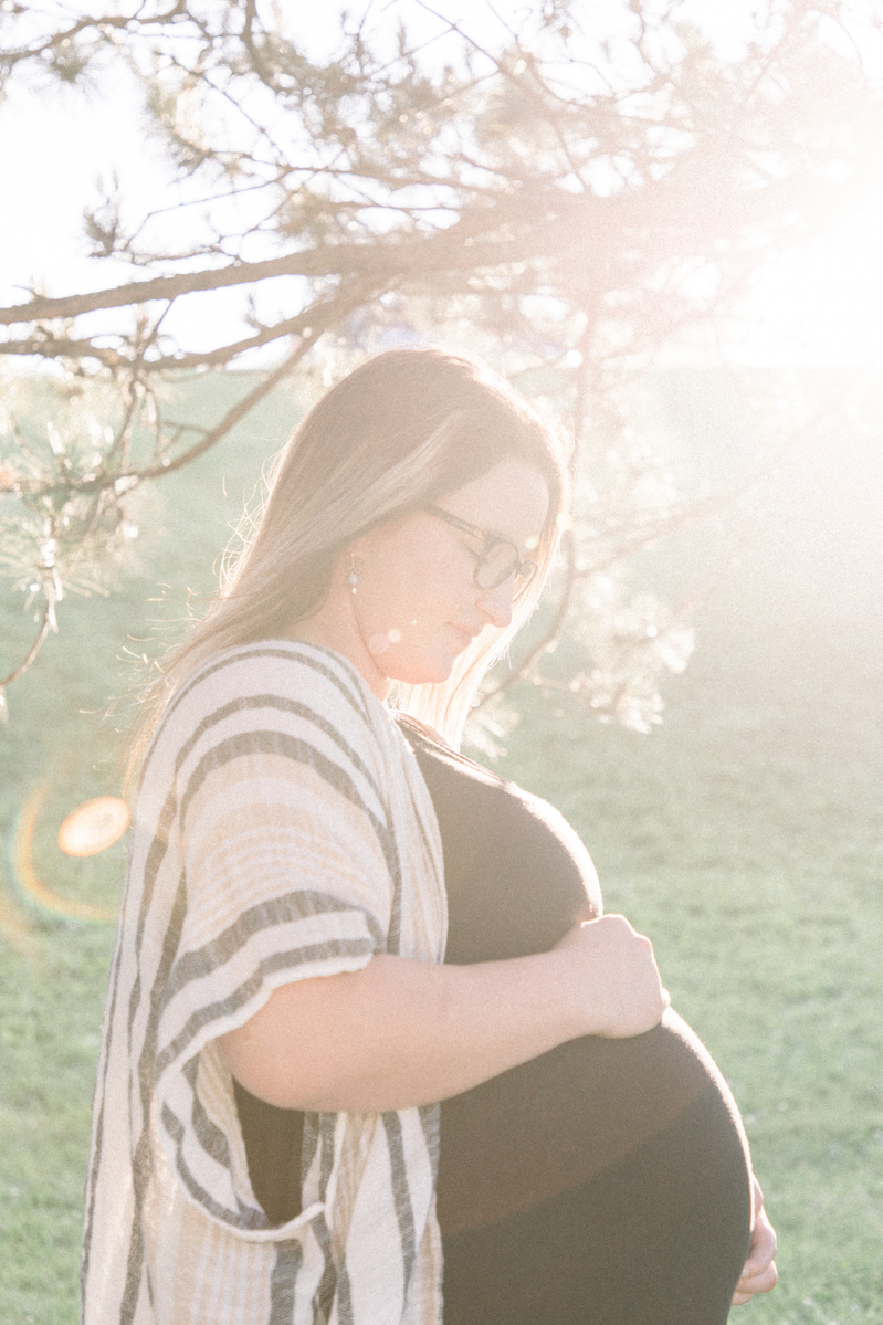 Maternity photo of woman looking at her bump at sunset, Emily VanderBeek Photography, Portrait and Family photography, Niagara Photographer, Champlain Photographer, Vaudreuil-Soulanges Photographer, candid photography, authentic photography.