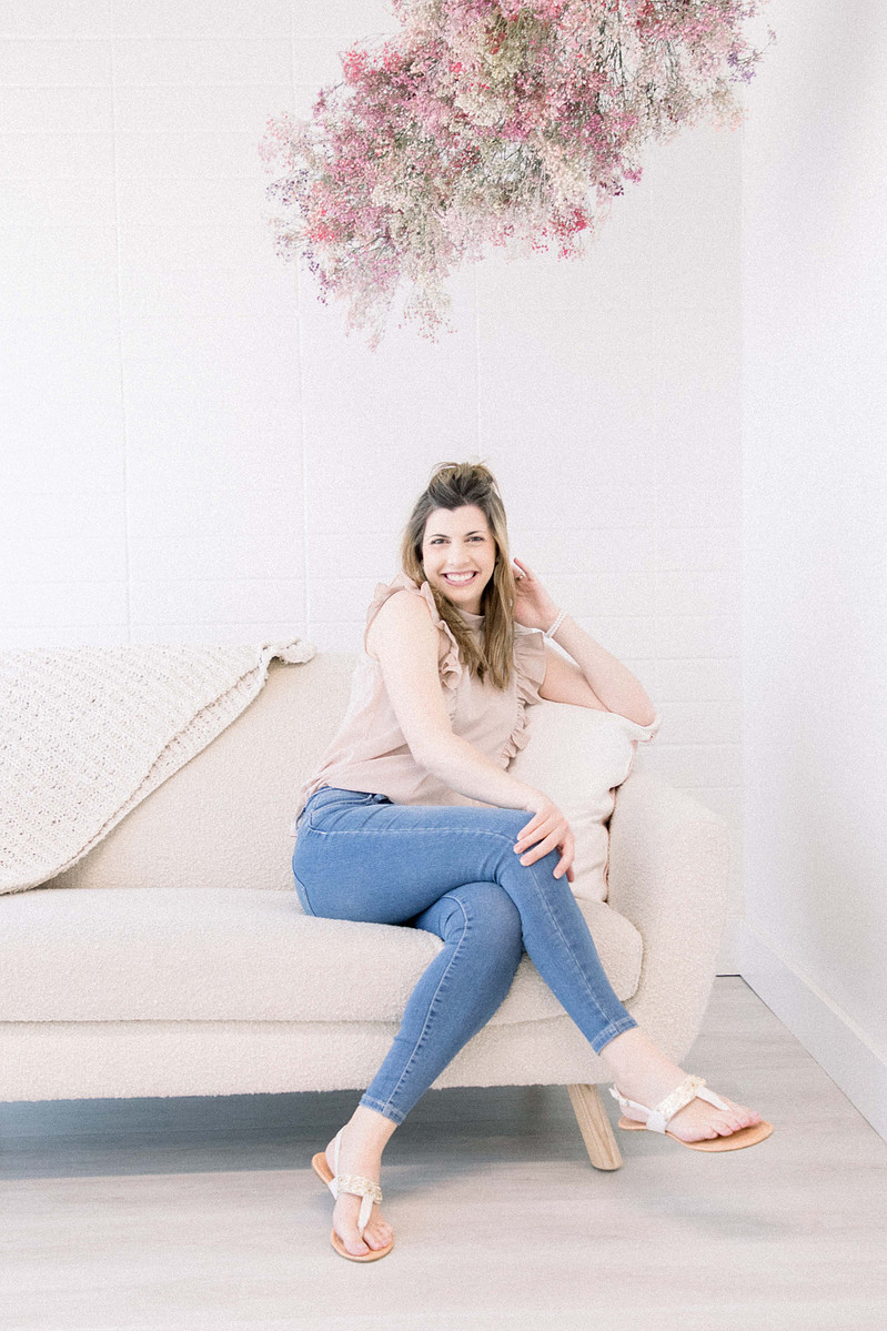 Woman sitting on couch in studio smiling into the camera, Emily VanderBeek Photography, Portrait and Family photography, Niagara Photographer, Champlain Photographer, Vaudreuil-Soulanges Photographer, candid photography, authentic photography.
