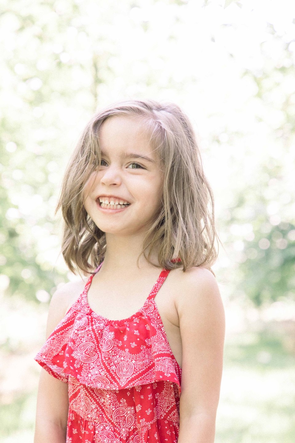 Portrait of young girl laughing while standing in fruit orchard, Niagara family photographer, Niagara portrait photographer, family photography, portrait photography, candid photography, authentic photography, Emily VanderBeek Photography.