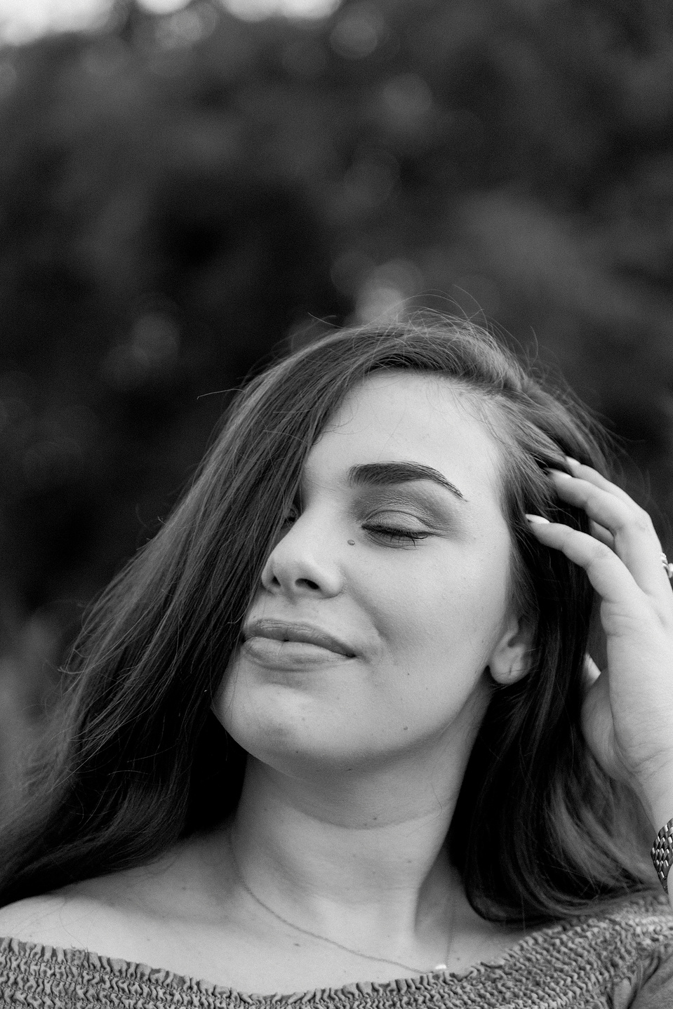 Close-up black and white portrait of woman with her eyes closed and playing with her hair. Niagara portrait photography, Niagara portrait photographer, Niagara branding photography, Niagara branding photographer.