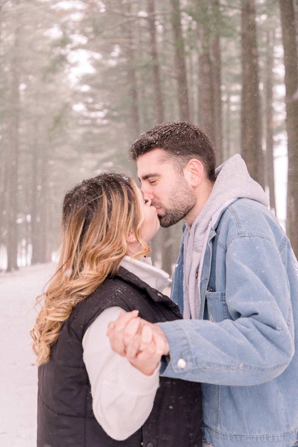 Portrait of young couple holding hands and kissing on a winter trail, Niagara family photographer, family photography, Niagara portrait photographer, portrait photography, Champlain photographer, Hawkesbury photographer, Emily VanderBeek Photography.