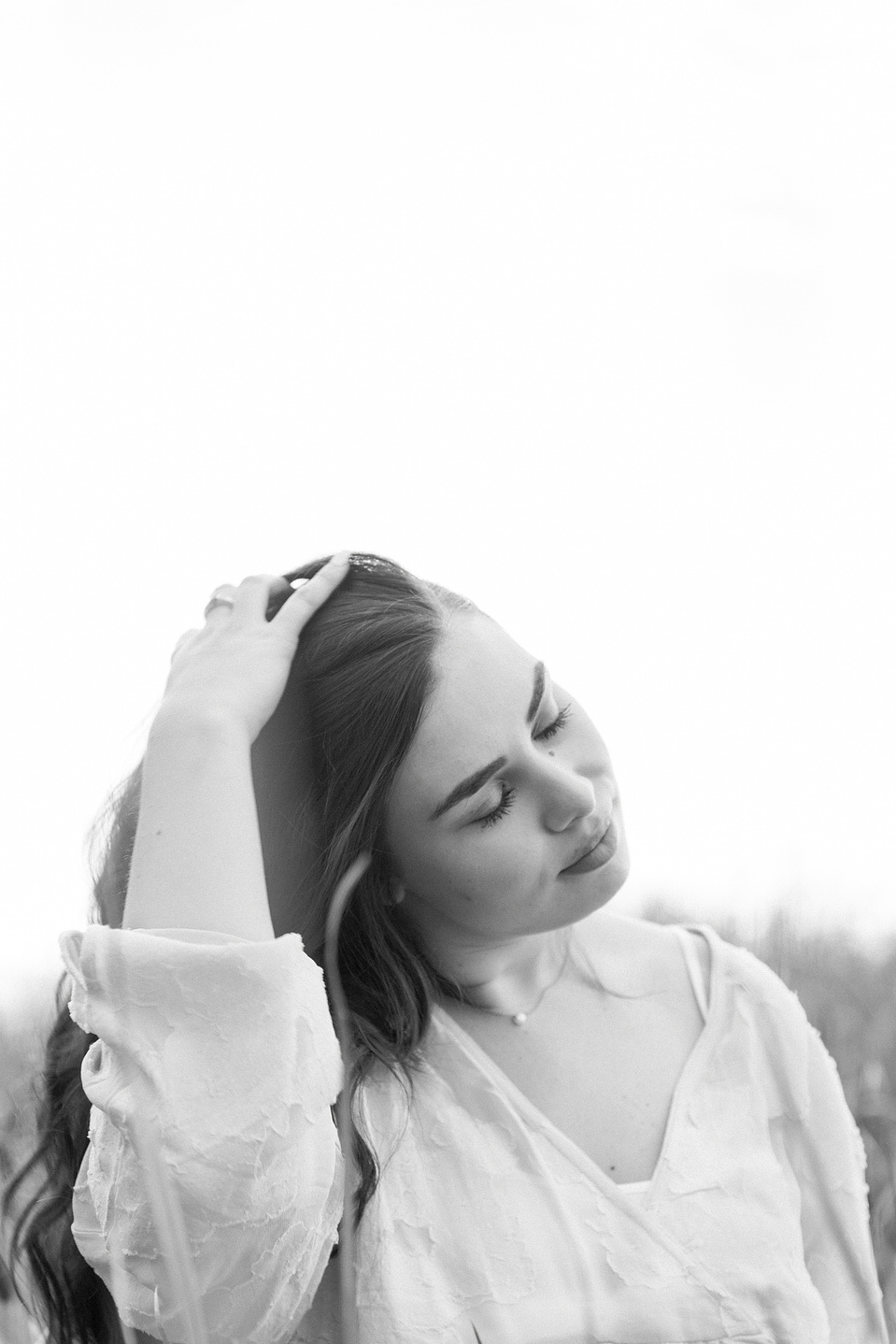 Close-up black and white portrait of woman playing with her hair with her eyes closed. Niagara portrait photography, Niagara portrait photographer, Niagara branding photography, Niagara branding photographer.