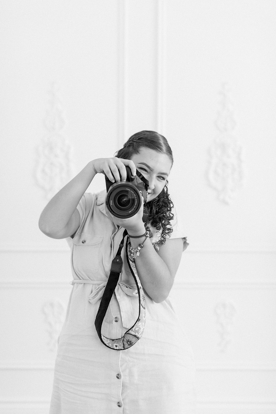 Black and white portrait of woman standing up holding camera. Niagara portrait photography, Niagara portrait photographer, Niagara branding photography, Niagara branding photographer, Niagara family photography, Niagara family photographer.