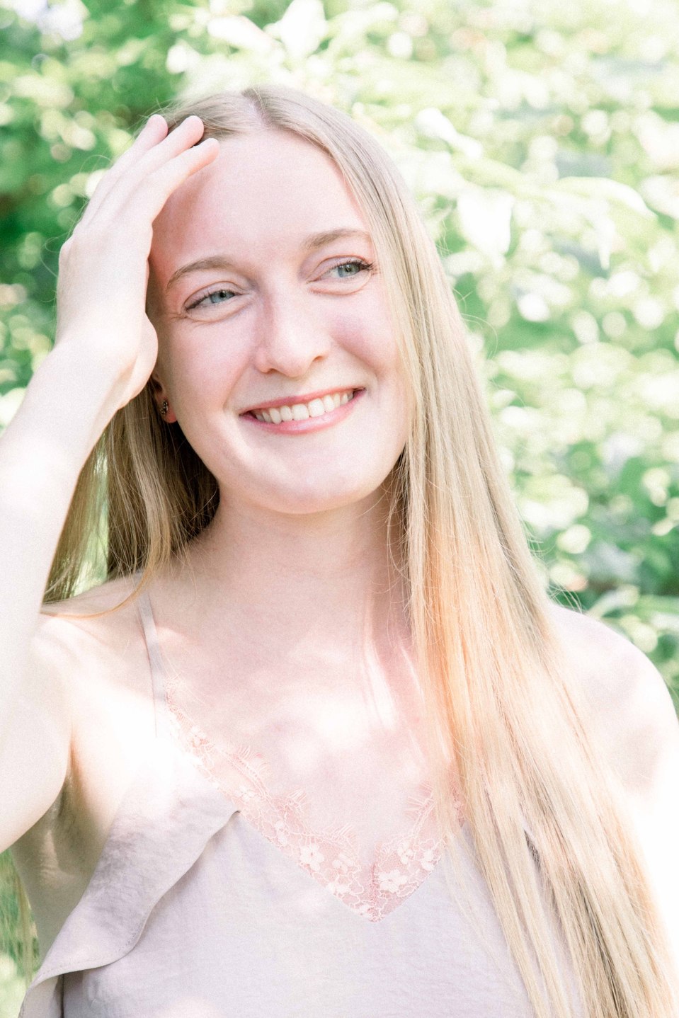 Portrait of woman laughing in fruit orchard while playing with her hair, Niagara family photographer, Niagara portrait photographer, family photography, portrait photography, candid photography, authentic photography, Emily VanderBeek Photography.