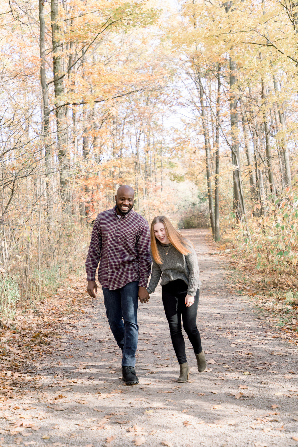 Portrait of couple walking down path, bumping hips and laughing. Niagara portrait photography, Niagara portrait photographer, Niagara family photography, Niagara family photographer.