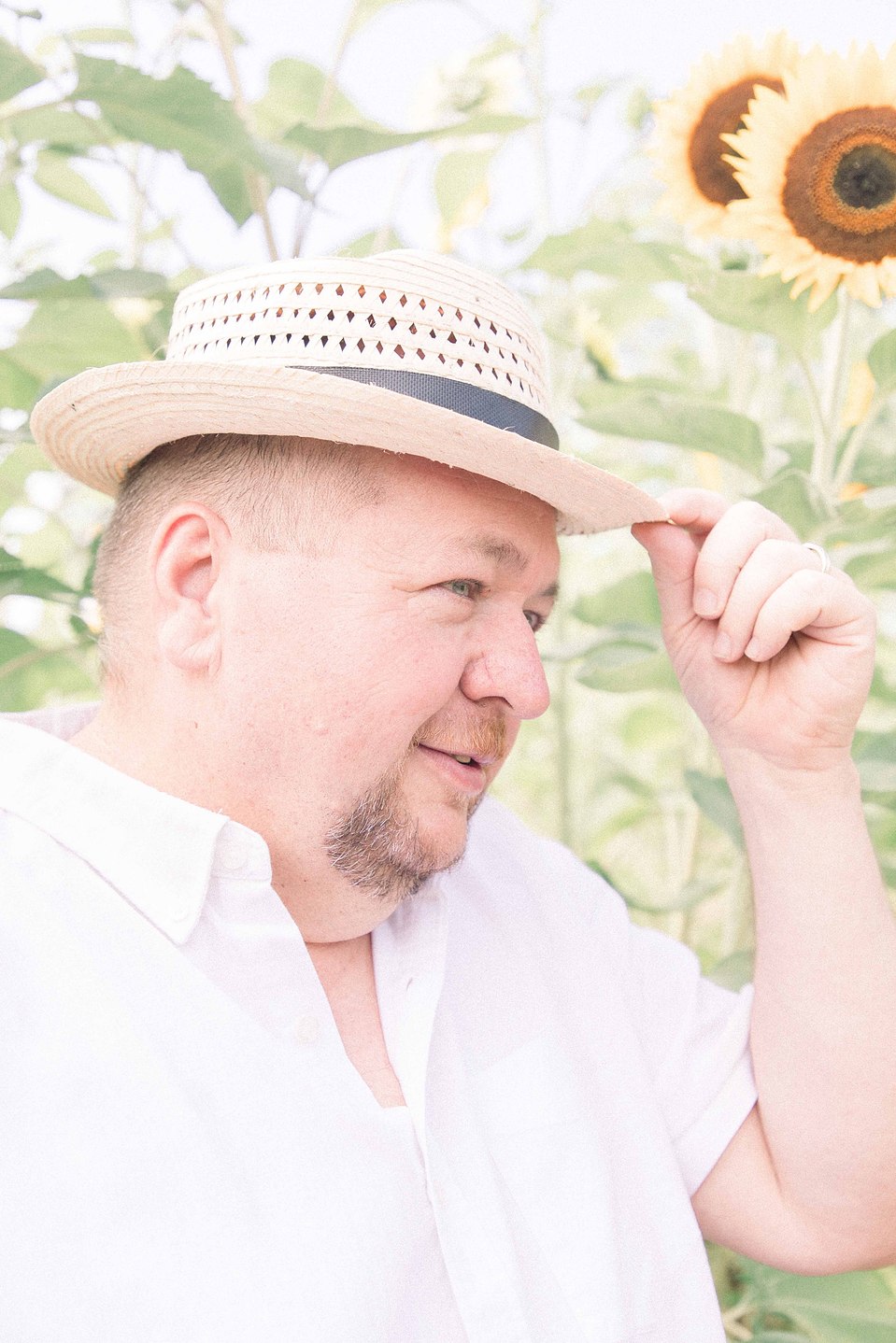 Portrait of man posing with his hat in a sunflower field, Niagara family photographer, family photography, Niagara portrait photographer, portrait photography, Emily VanderBeek Photography.