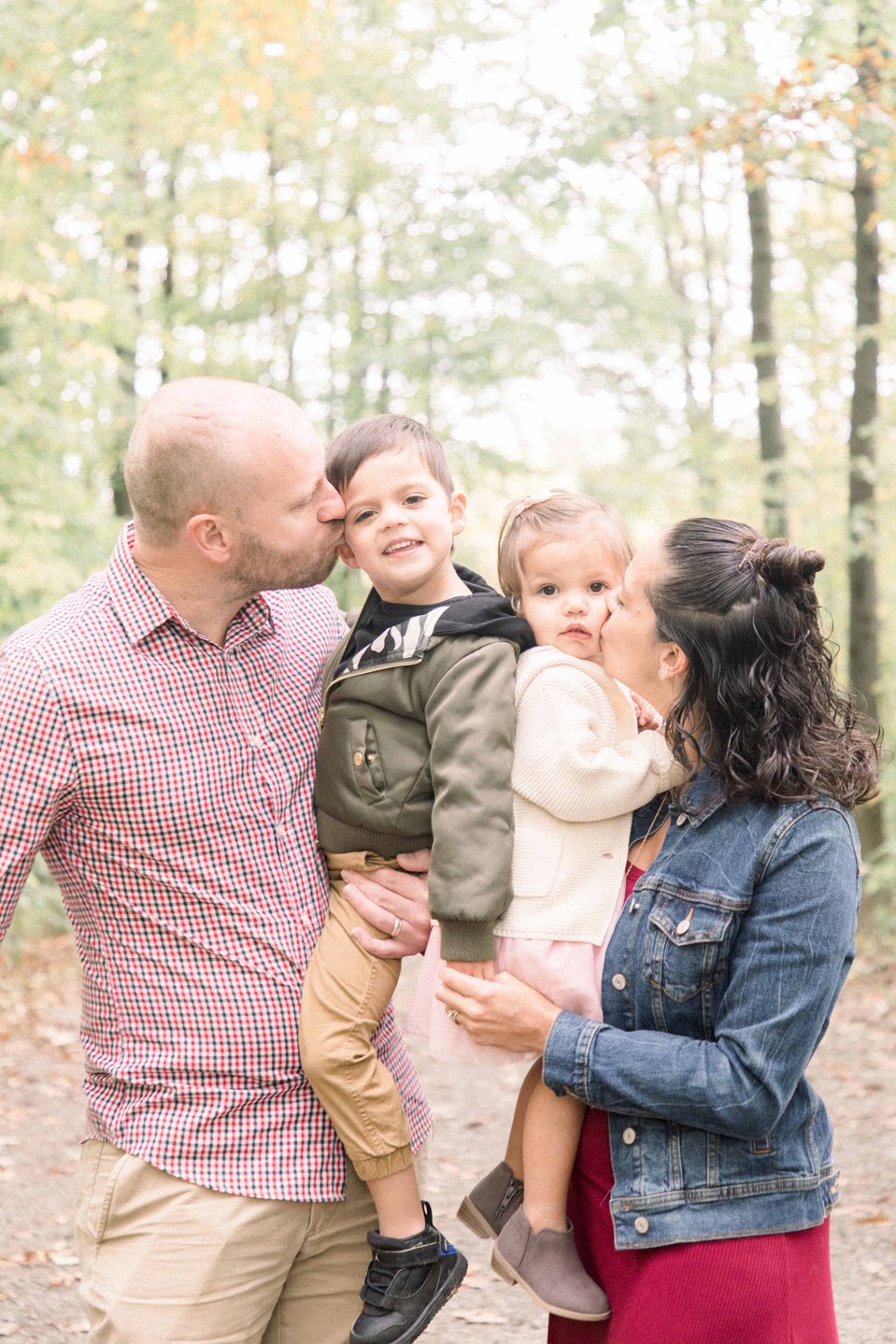 Portrait of a family of four with parents holding kids and kissing them on the cheeks, Fall photos, Niagara family photographer, family photography, Niagara portrait photographer, portrait photography, Emily VanderBeek Photography.