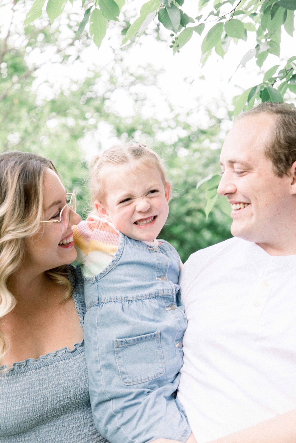 Portrait of family of three hugging and laughing in fruit orchard, Niagara family photographer, Niagara portrait photographer, family photography, portrait photography, candid photography, authentic photography, Emily VanderBeek Photography.