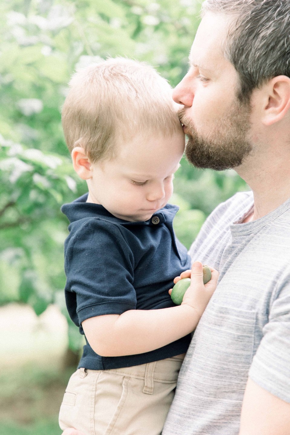 Portrait of father kissing his son on the forehead in orchard, Niagara family photographer, Niagara portrait photographer, family photography, portrait photography, candid photography, authentic photography, Emily VanderBeek Photography.