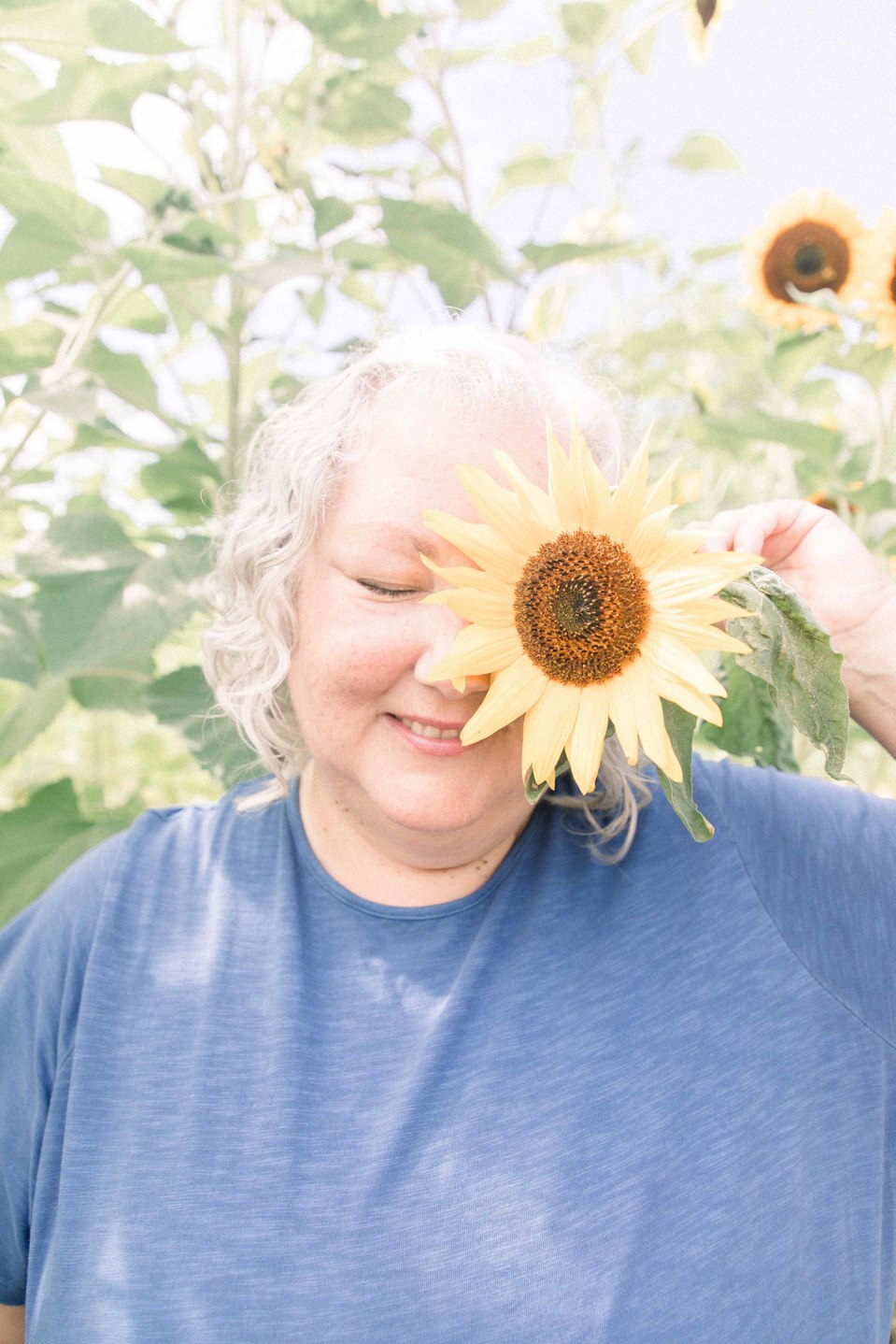 Candid portrait of a woman playing with flowers in a sunflower field, Niagara family photographer, family photography, Niagara portrait photographer, portrait photography, Emily VanderBeek Photography.
