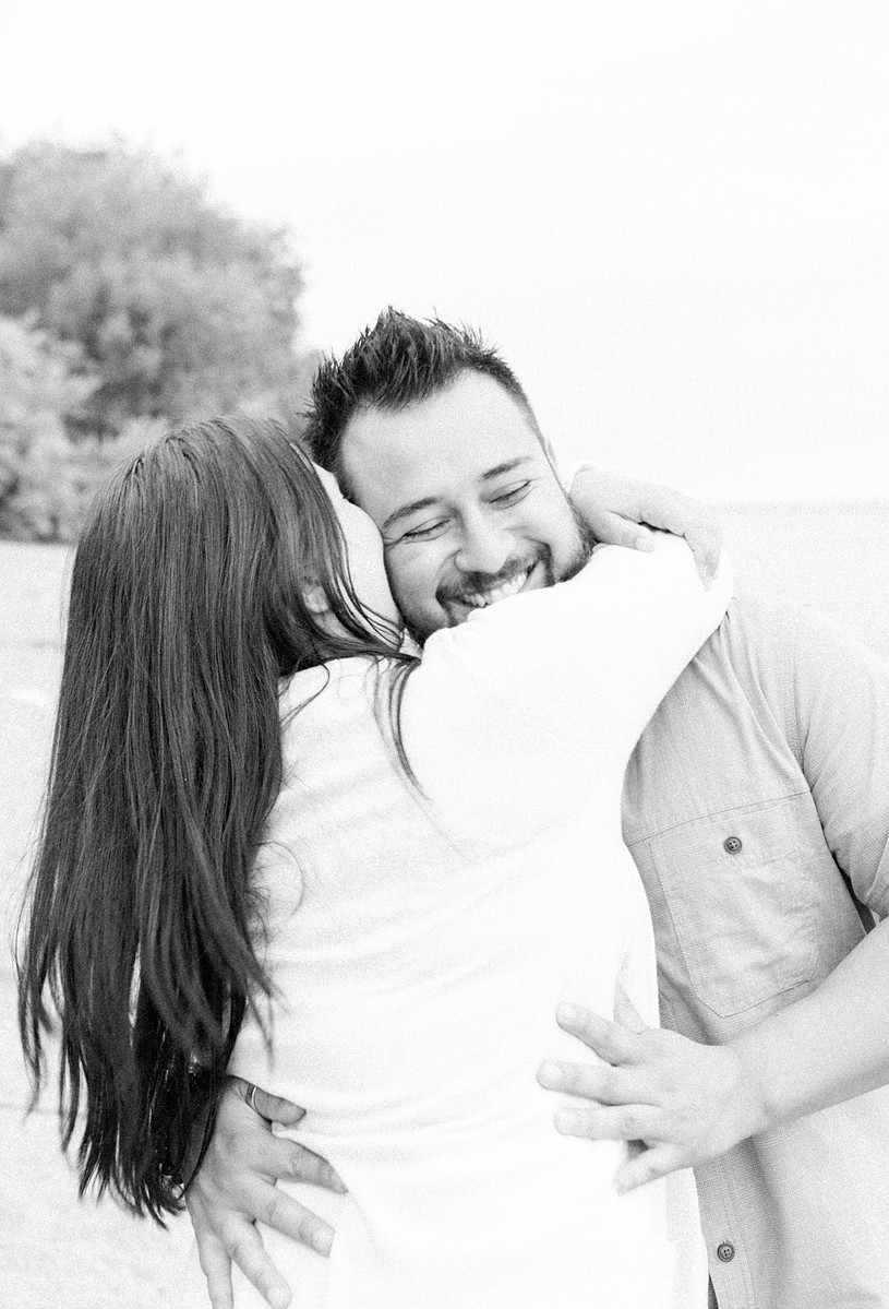 Black and white photo or couple hugging and laughing on the beach, Emily VanderBeek Photography, Portrait and Family photography, Niagara Photographer, Champlain Photographer, Vaudreuil-Soulanges Photographer, candid photography, authentic photography.