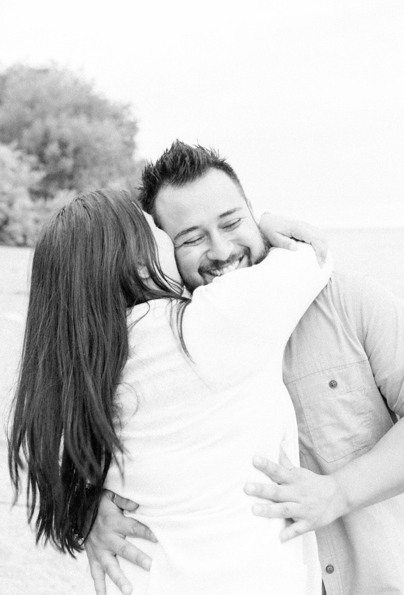 Black and white photo or couple hugging and laughing on the beach, Emily VanderBeek Photography, Portrait and Family photography, Niagara Photographer, Champlain Photographer, Vaudreuil-Soulanges Photographer, candid photography, authentic photography.