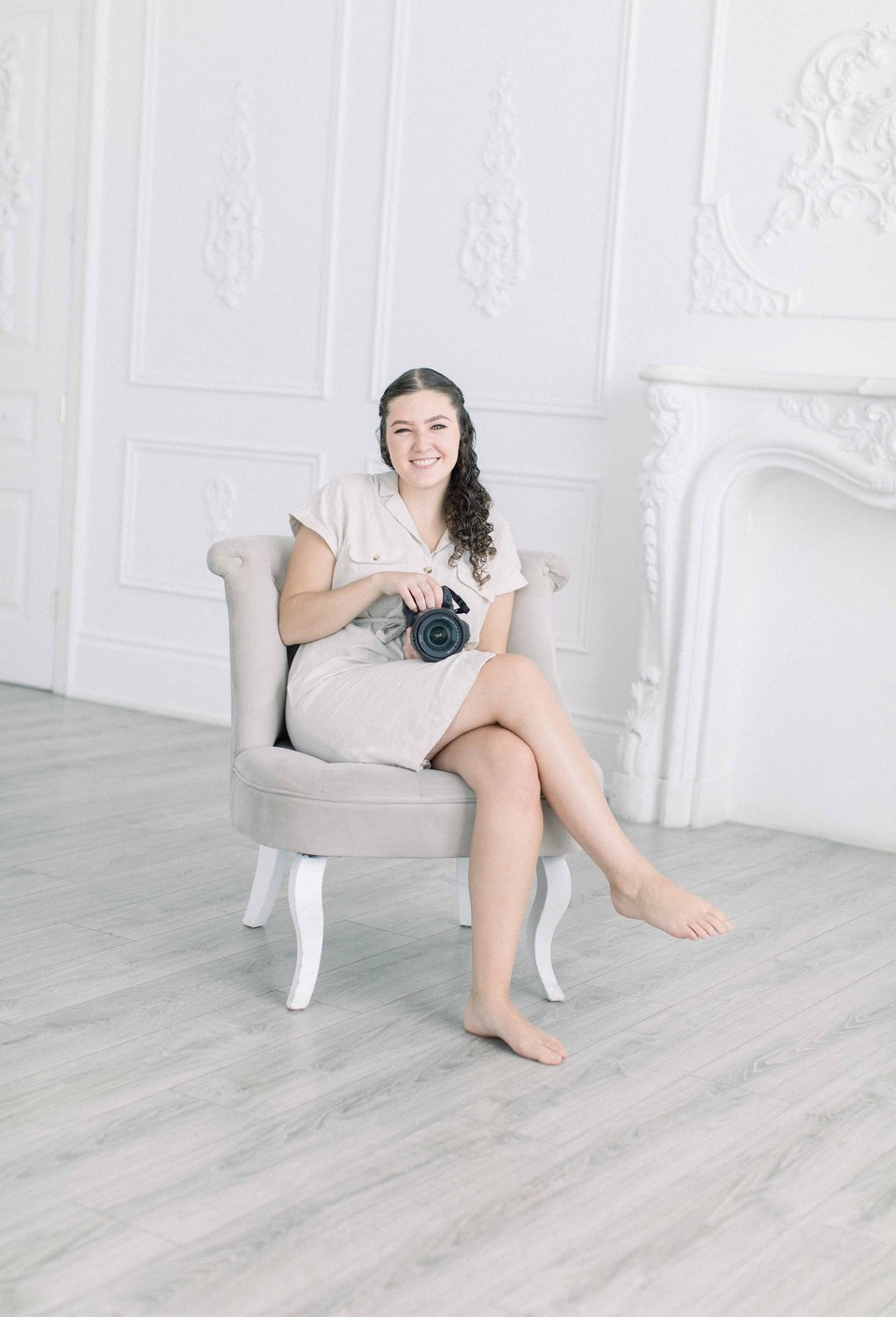 Portrait of woman sitting on chair smiling while holding a camera. Niagara portrait photography, Niagara portrait photographer, Niagara branding photography, Niagara branding photographer, Niagara family photography, Niagara family photographer.