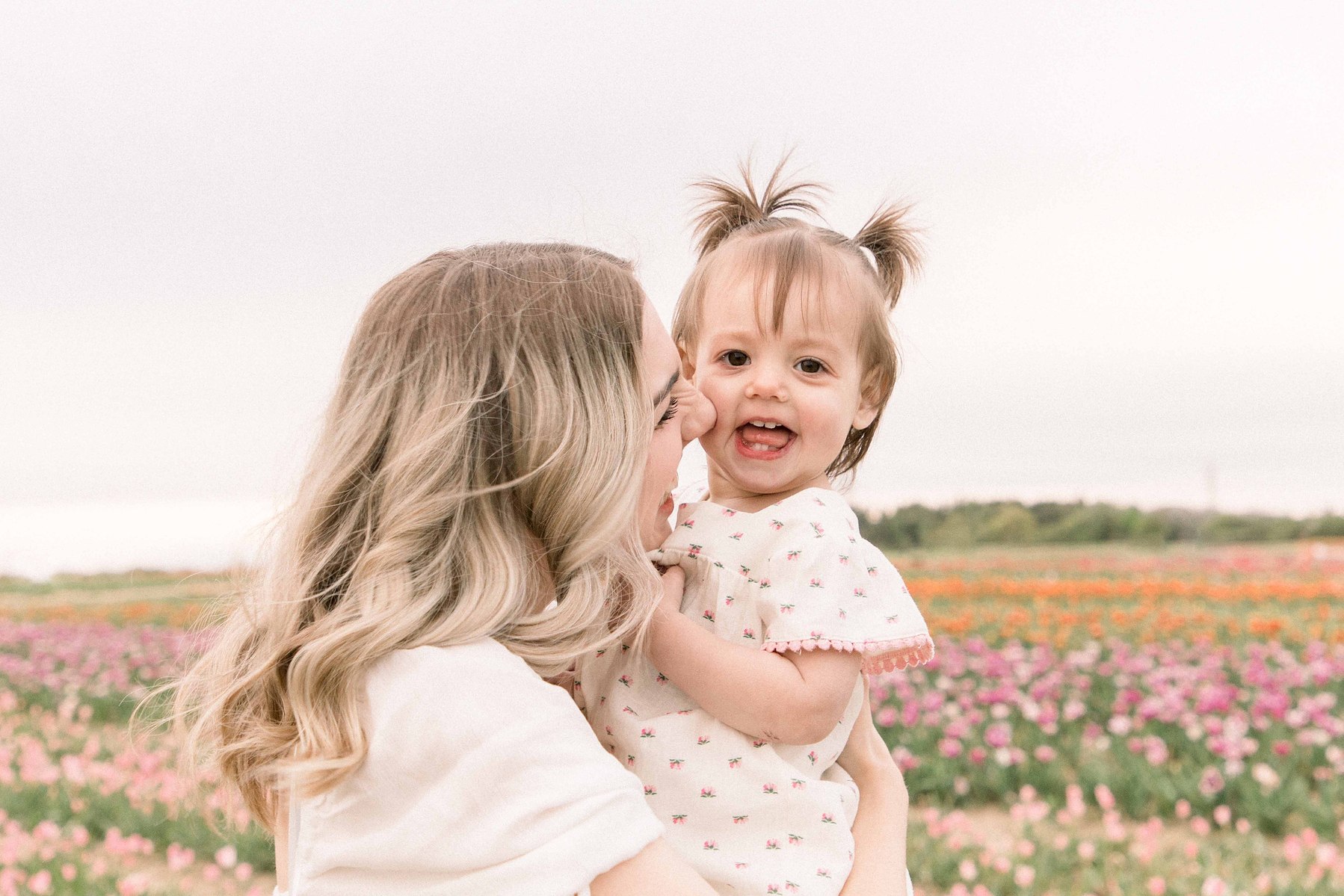 Portrait mom and daughter at a tulip field in Niagara, kissing her on the cheek. Niagara portrait photographer. Niagara family photographer. Niagara photographer. Emily VanderBeek Photography. Candid photography. Light and airy photography