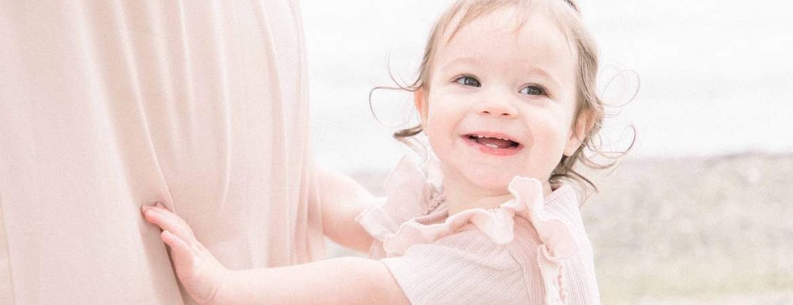 Candid portrait of little girl playing with mother's dress on beach, Emily VanderBeek Photography, Portrait and Family photography, Niagara Photographer, Champlain Photographer, Vaudreuil-Soulanges Photographer, candid photography, authentic photography.