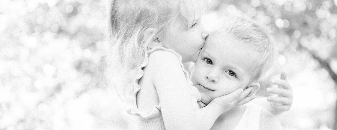 Black & white portrait of girl kissing her brother on the cheek, Emily VanderBeek Photography, Portrait and Family photography, Niagara Photographer, Champlain Photographer, Vaudreuil-Soulanges Photographer, candid photography, authentic photography.