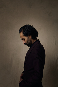 Dark, moody studio portrait of a man sitting in a chair. Photographed at South Facing Windows studio in Chicago, Illinois.