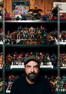 Environmental portrait of ​Comic cartoonist Tim Seeley in front of his collection of action figure collectibles. Photographed in Chicago for Chicago Magazine