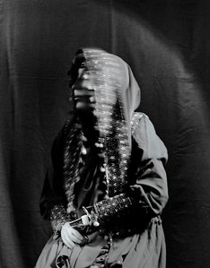 Black and white medium format portrait of an afghan woman, with a blurred face and two faux hands that she lost in an explosion. Wearing traditional afghan clothing. Nekbahkt survived a suicide bomb explosion in Afghanistan in 2007 but lost her arms and m