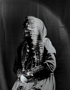 Black and white medium format portrait of an afghan woman, with a blurred face and two faux hands that she lost in an explosion. Wearing traditional afghan clothing. Nekbahkt survived a suicide bomb explosion in Afghanistan in 2007 but lost her arms and m