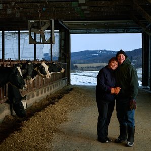 Image of dairy farmers in Upstate New York, standing next to their dairy cows. 