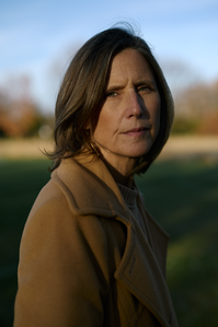 Solemn portrait of a woman looking into the camera, with sun on her face at a park in Chicago. For a story about cancer and medical malpractice by medical companies treating cancer patients. 