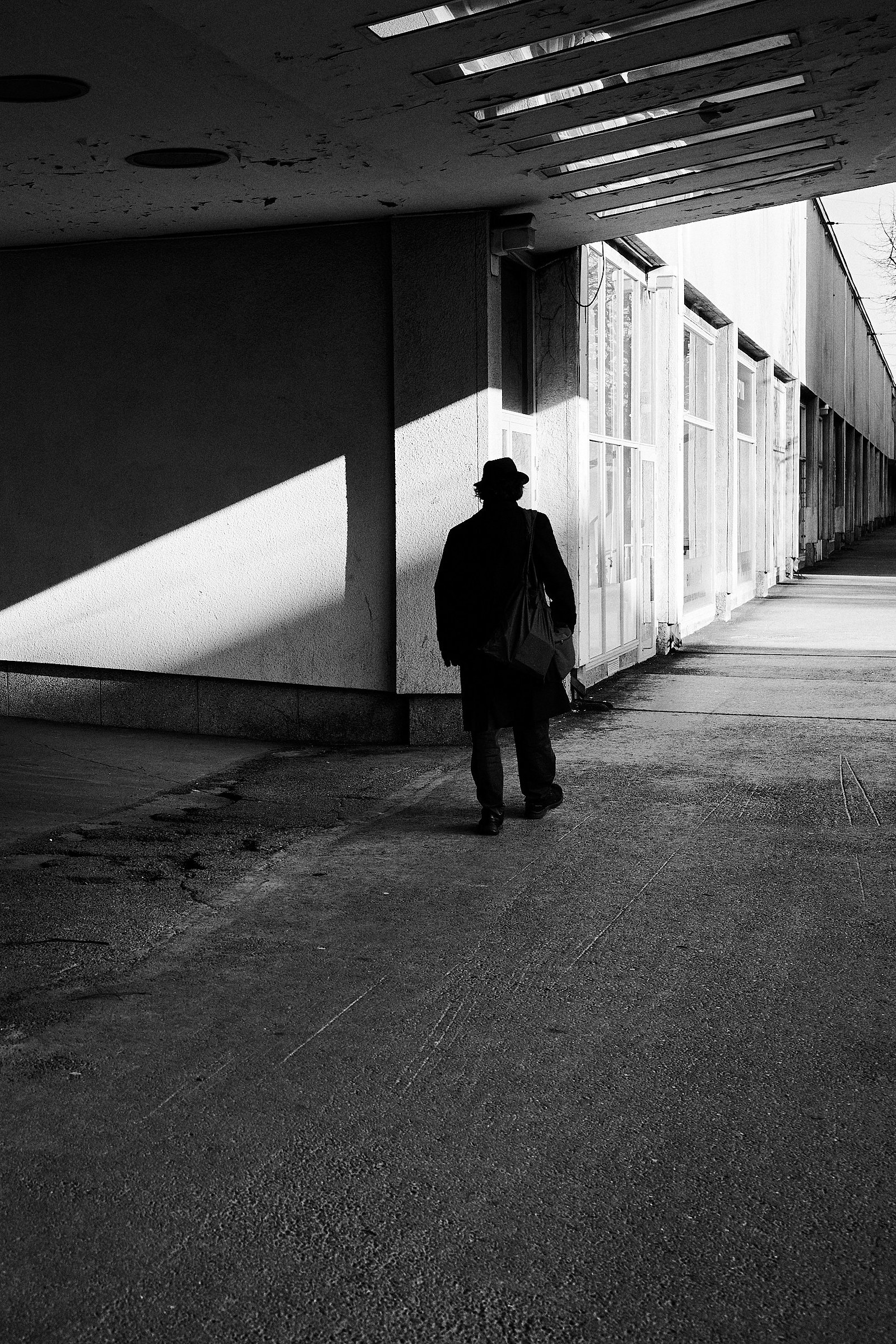 Solitary man wearing dark clothes and a hat walks next to Helsinki Kisahalli