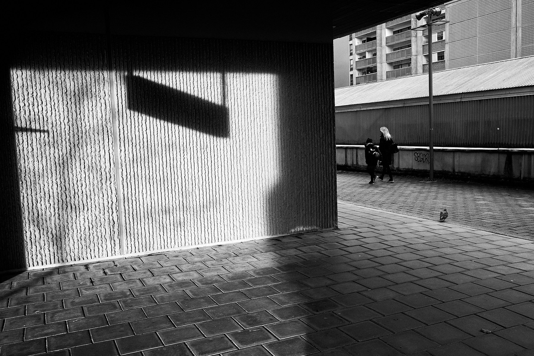A woman and boy are walking surrounded by concrete buildings in Merihaka, Helsinki