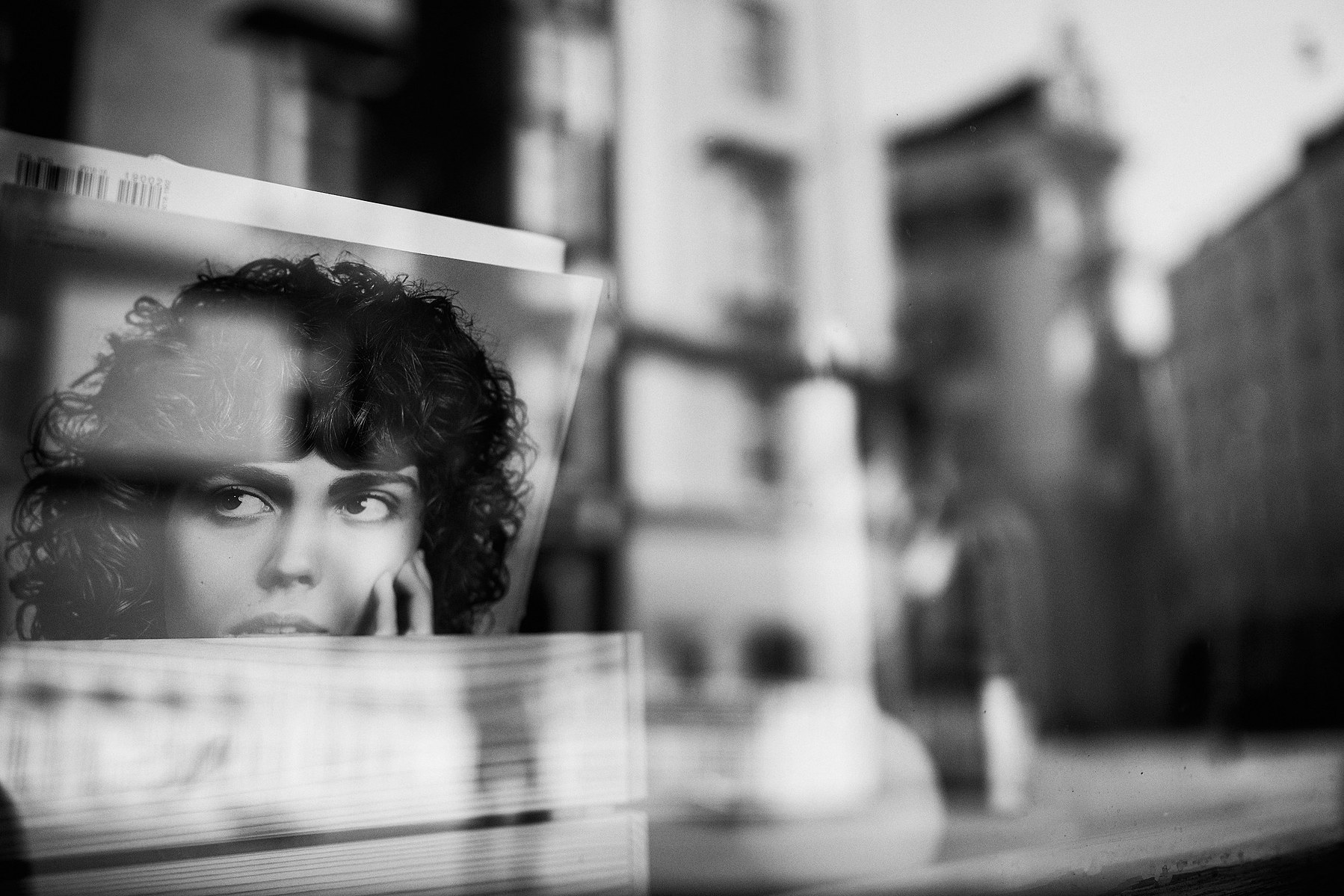 A woman's face on the record cover stares through a shop window that reflects surroundings