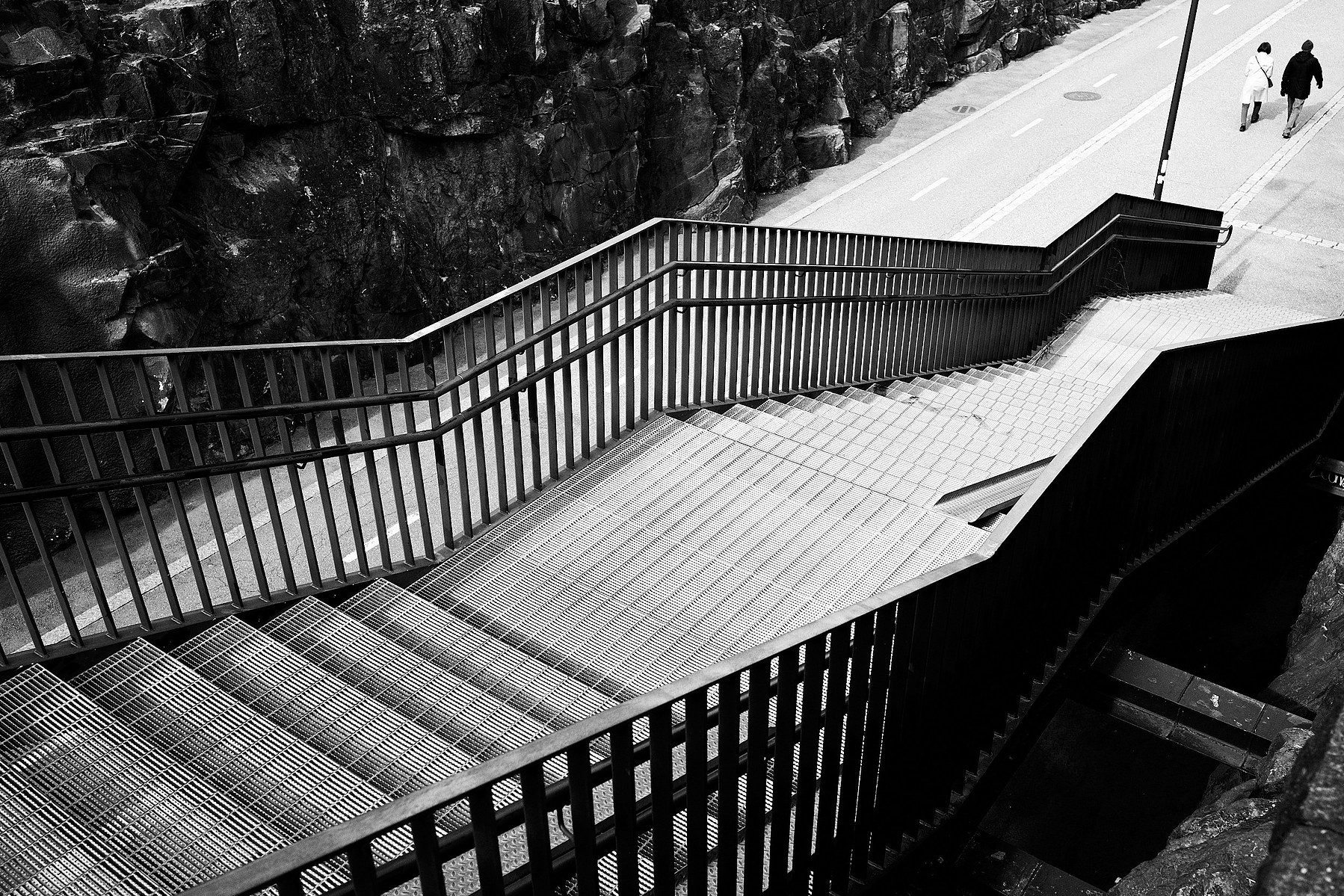 A pair walks on the street passing a stairway