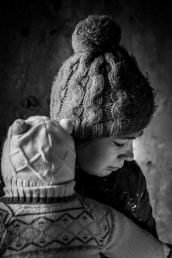 A portrait of a mother holding her baby. She is homeless and takes shelter in an abandoned building in Moscow.