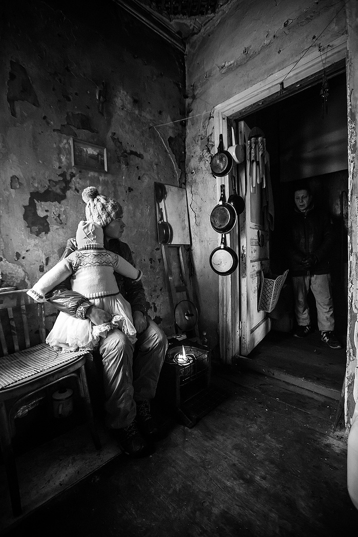 A portrait of a mother holding her baby. She is homeless and takes shelter in an abandoned building in Moscow. The baby is not real, it is a toy doll.