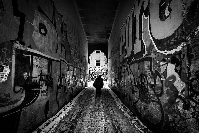 A man walks down a graffiti covered alleyway towards an abandoned building in Moscow.