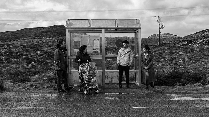 Refugee family from Afghanistan wait for a bus on the Isle of Lewis, Scotland.