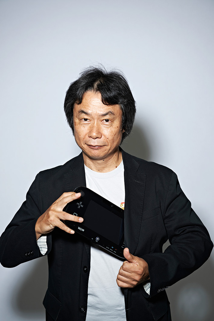 Portrait of nintendo game designer Miyamoto Shigeru taking a Wii U out of his jacket